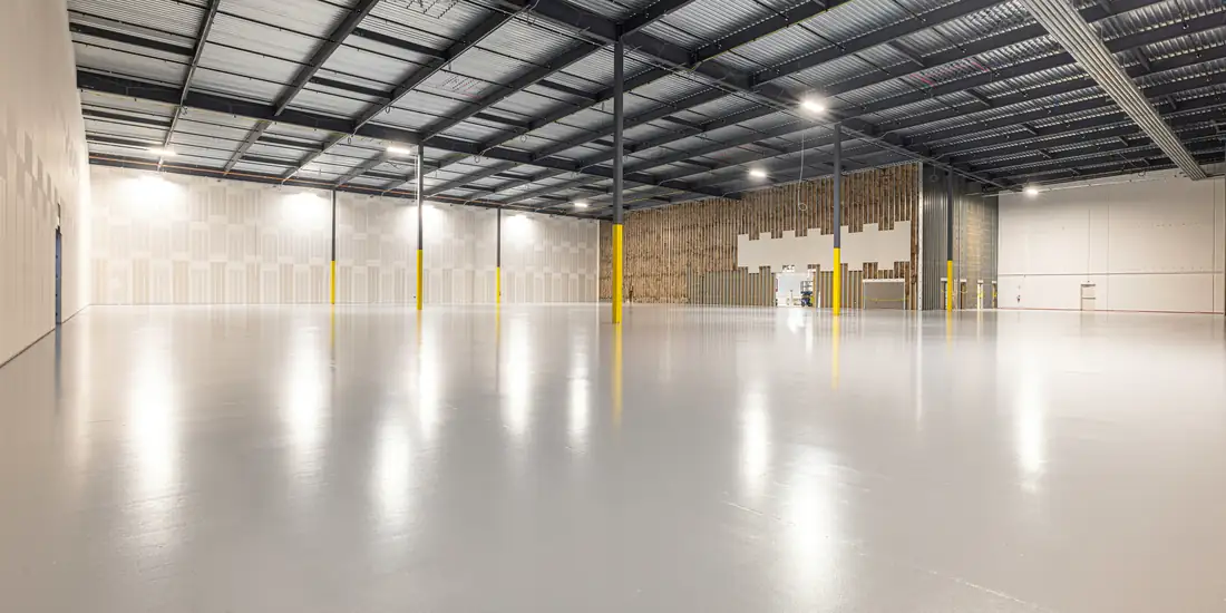 A person standing alone in a large empty industrial warehouse
