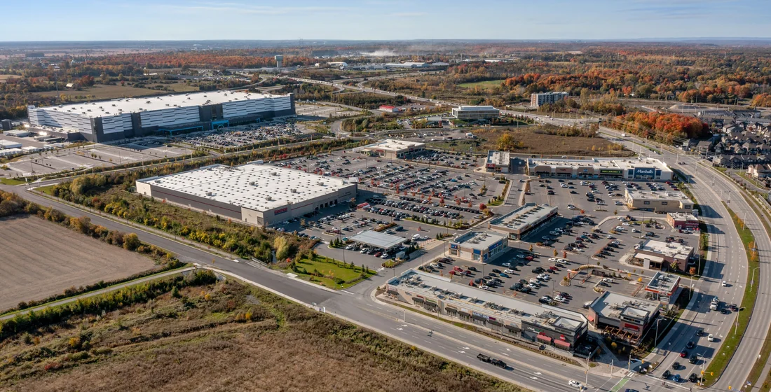 Aerial view of a large warehouse with car parking and service roads around it, and undeveloped ground beyond