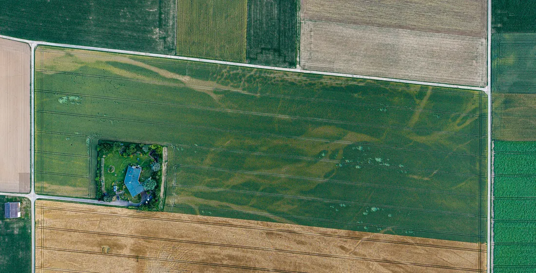 Aerial view of farmland divided into distinct rectangular parcels with hard boundaries between them