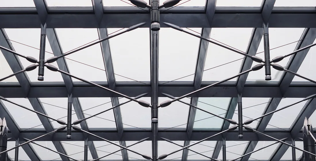 Steel roof truss and glazing seen from below inside an industrial building