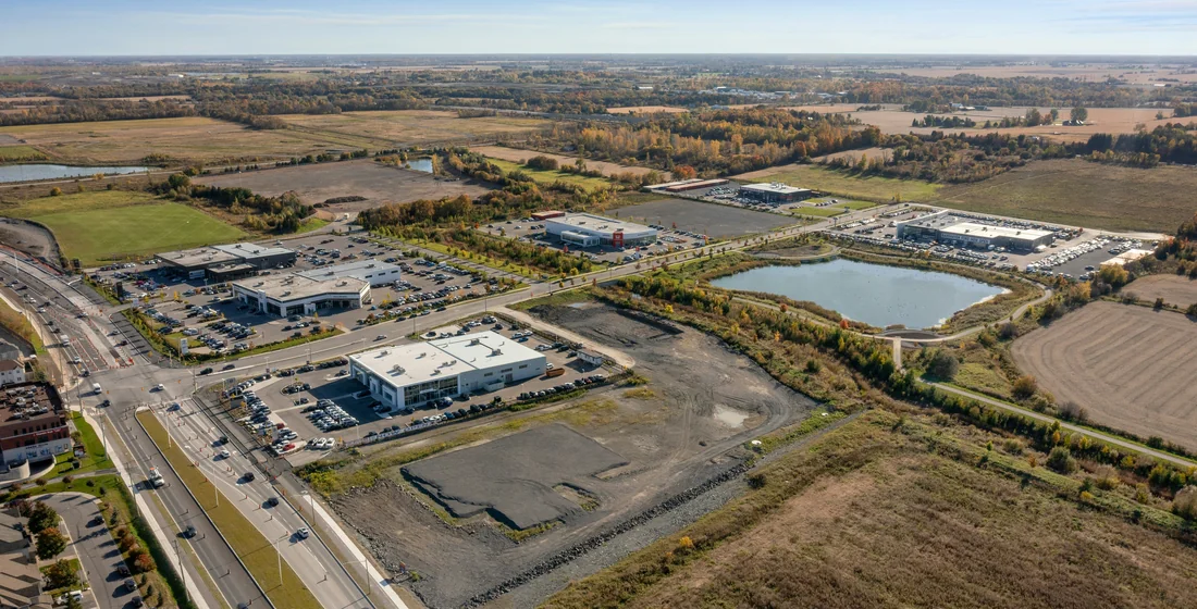 Aerial view of an area mixing developed buildings and car parks with large undeveloped brown parcels