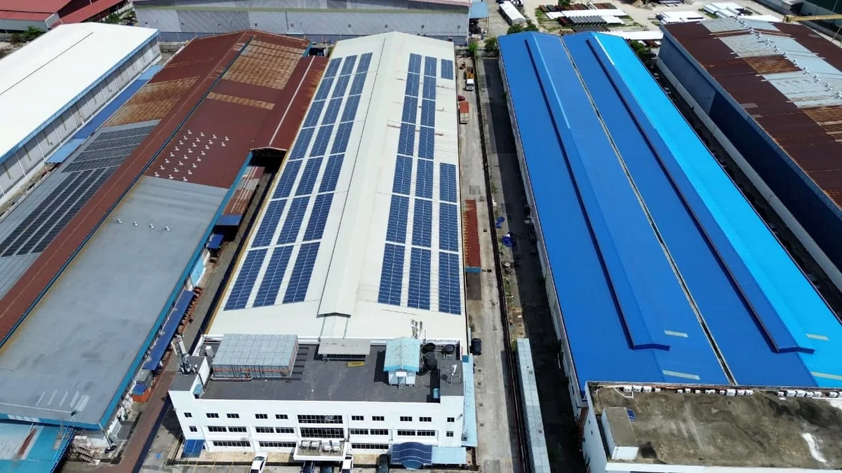 Aerial view across an industrial estate with several roof types in one frame, long single span roofs on one side and smaller repeated roof bays on the other, separated by service roads