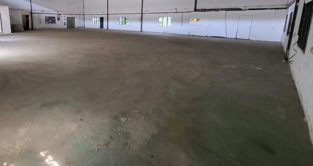 Older warehouse with a worn concrete floor showing staining, wear patterns and tyre tracks