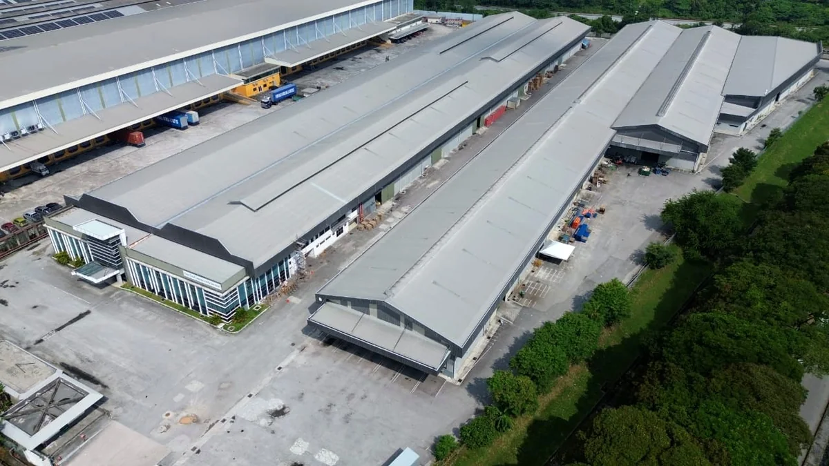 Rows of terrace factory units seen from above, repeated roof bays sharing continuous party walls, with a service road running between two facing rows and vehicles parked on the forecourts